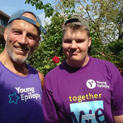 Young man and older man, in Young Epilepsy T-shirts, smile a the camera