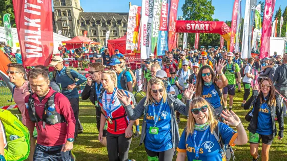 Walkers under a start line surrounded by flags