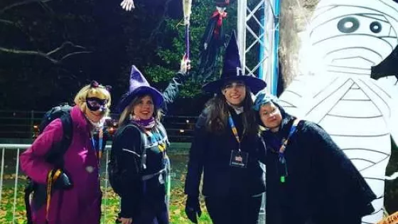 4 women in Halloween costumes posing with a mummy