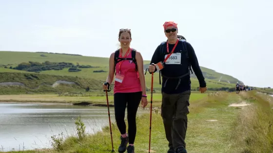 A woman and man walking with poles next to a lake