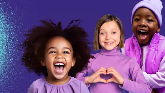 Three young children smiling and wearing purple