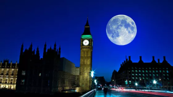 Big ben at night with a full moon in the sky 