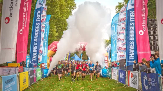 Group of people walking through event start line with smoke blasting above them