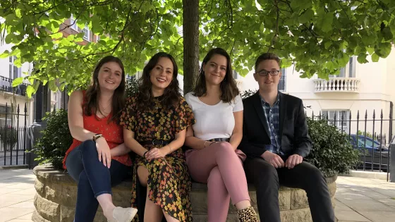 group of young people sat under a tree