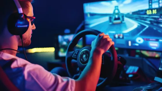 Racing simulator driver - young man with hands on wheel