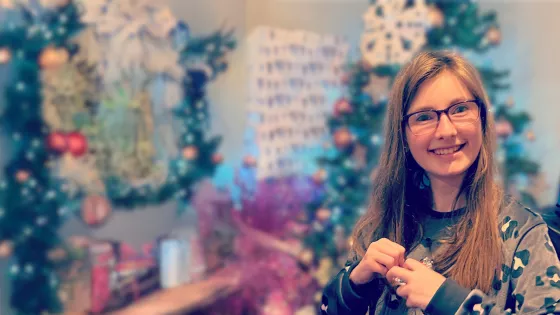 Young girl smiling next to a Christmas tree