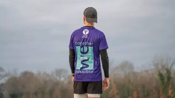 Young man poses from the back in a Young Epilepsy t-shirt