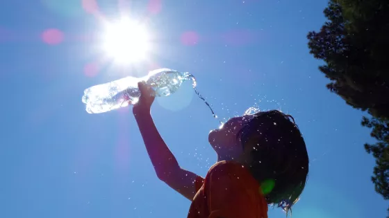 young child pours water from a bottle in the hot sun