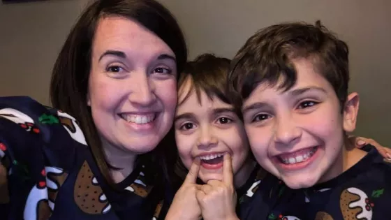 A woman and her two sons smile in a selfie wearing Christmas jumpers.