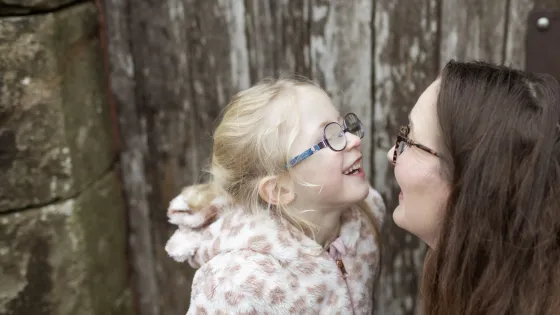 A mother and daughter smile at each other.