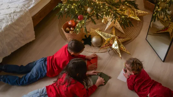 A group of children gather under a Christmas tree.