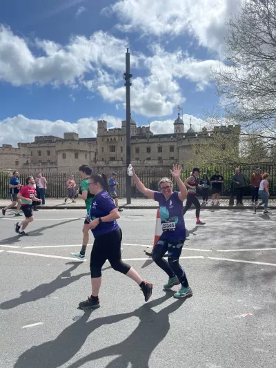 Two female runners, one waving as they pass