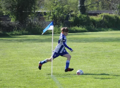 Boy in blue and white football kit kicking a ball