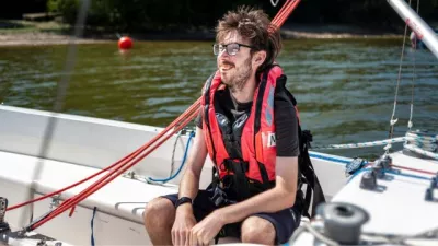 Young man wearing a life vest sat on a sailing boat