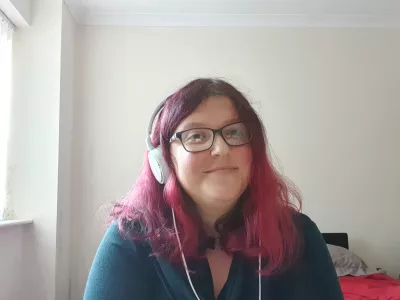 Annie - a young girl with red hair smiling at the camera with headphones on