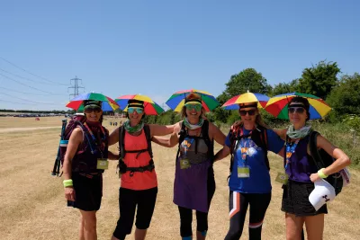 Group of 5 ladies posing for photo in umbrella hats