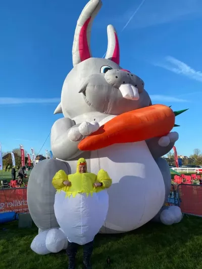 Person in a inflatable chick costume in front of a giant inflatable easter bunny 