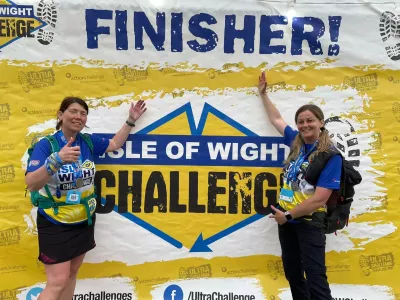 2 ladies posing with isle of white ultra challenge finisher sign