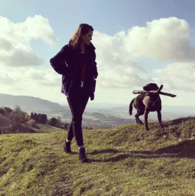 a girl walking her dog on a hill