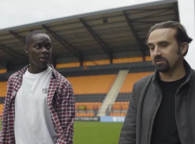 2 people walking on a football pitch