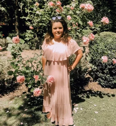 a young woman standing in a rose garden