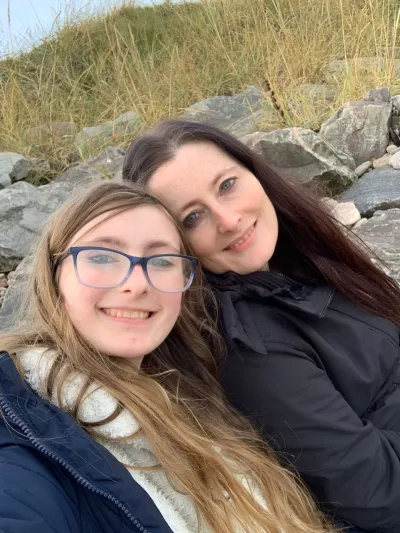 Mum and daughter smiling at a beach