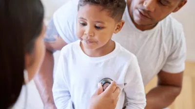 A son is being checked over by a healthcare professional while parent watches over