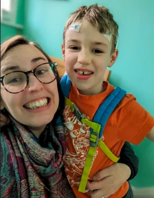 Mum smiling alongside her son having an EEG