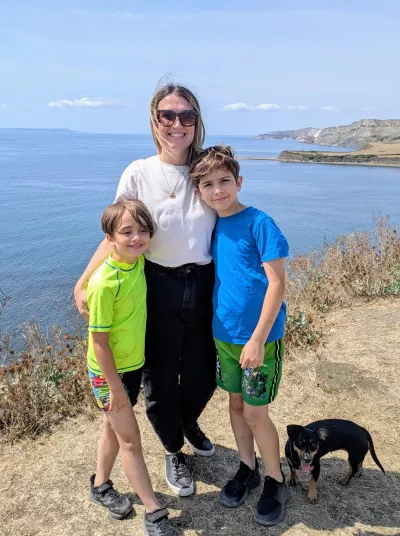 A mother, her two children, and their small dogs stand on a cliff overlooking the ocean.