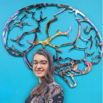 A young woman stands in front of a brain-shaped sculpture.