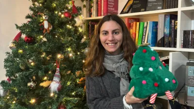 A young woman stands before a Christmas tree.