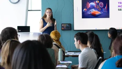 A woman teaches a room of young adults.