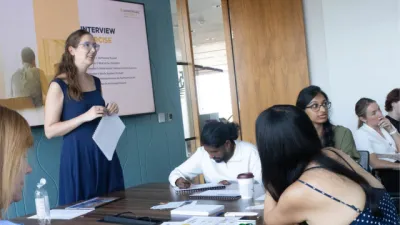 A woman stands before a class of young adults.