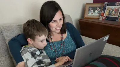 A mother and son look at a laptop.