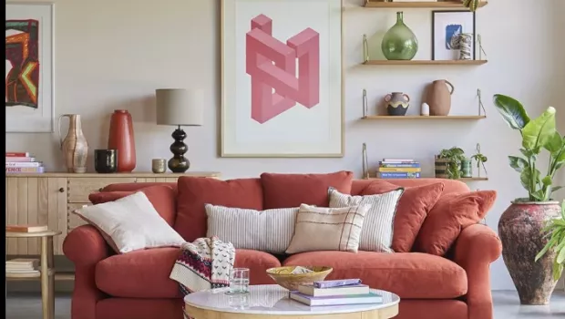 A peachy pink sofa in a living room with artwork and shelves in the background