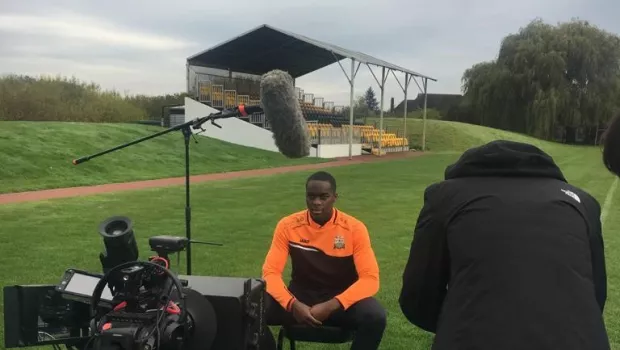 young man filming on a football pitch