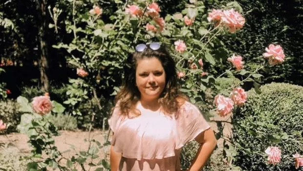 young woman standing in a rose garden