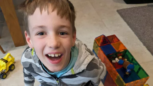 Young boy smiles while playing with his toys