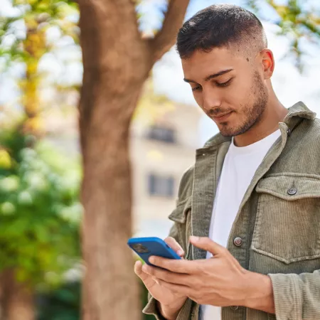 Young boy smiling confident using smartphone at park