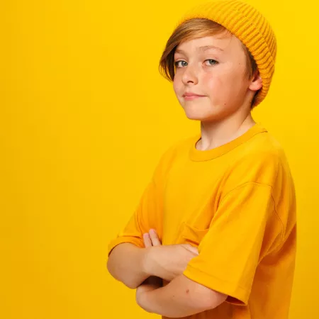 Cash against a yellow background smiling to the camera