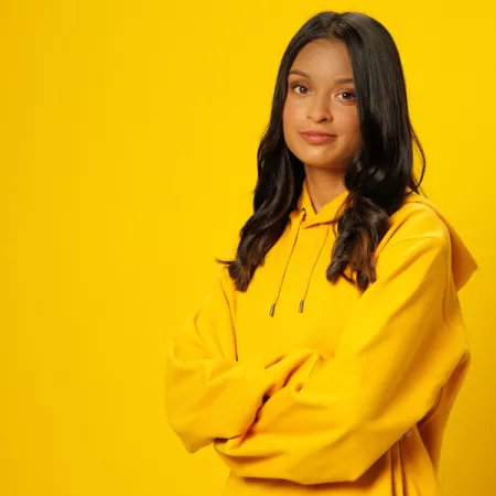 Jasmine against a yellow background smiling to the camera