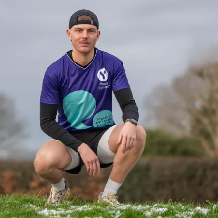 A young man poses in a Young Epilepsy t-shirt