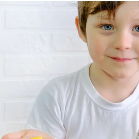 A young boy holds a glass and medication.