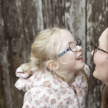 A mother and daughter smile at each other.