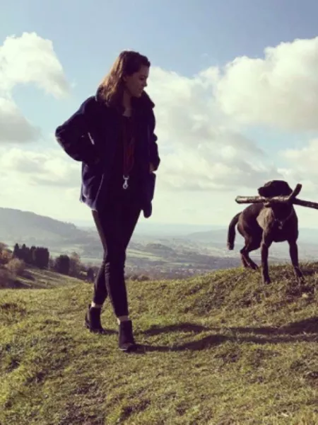 a girl walking her dog on a hill