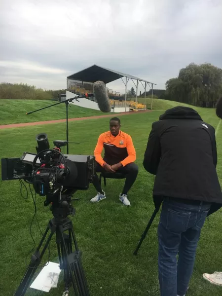 young man filming on a football pitch