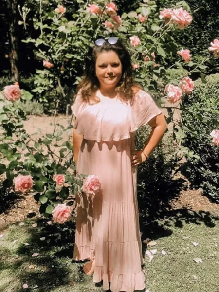 a young woman standing in a rose garden