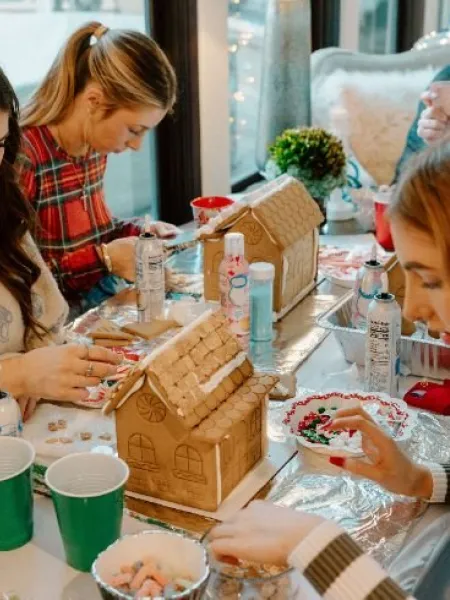 Three teenage girls design gingerbread houses.