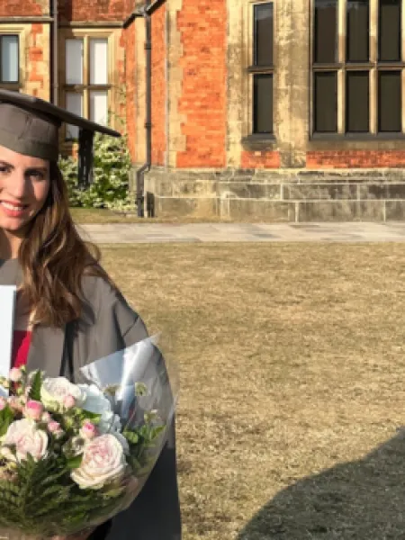 A young woman holds her degree at graduation.
