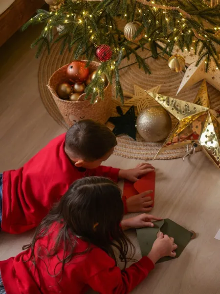 Children gather under a Christmas tree.